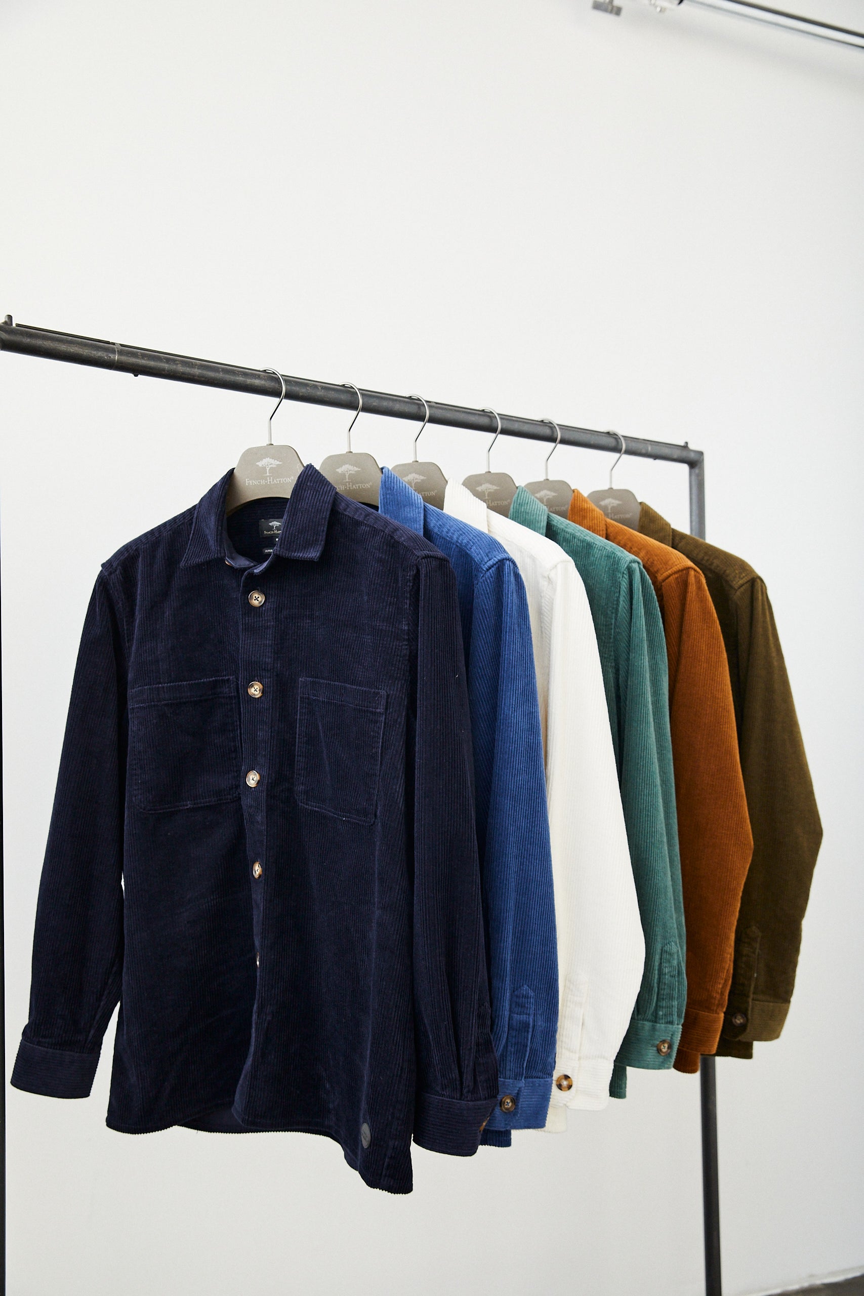 Overshirts an einer Kleiderstange hängend in Blau, Grün, Weiß, Braun und Senf